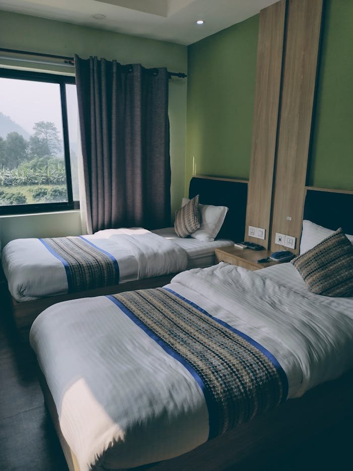 about-us-01 Luxurious hotel room interior with twin beds and a scenic window view.